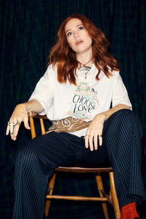 White Choose Love T-shirt featuring a colourful graphic print, styled with navy pinstripe trousers on Angela Scanlon.