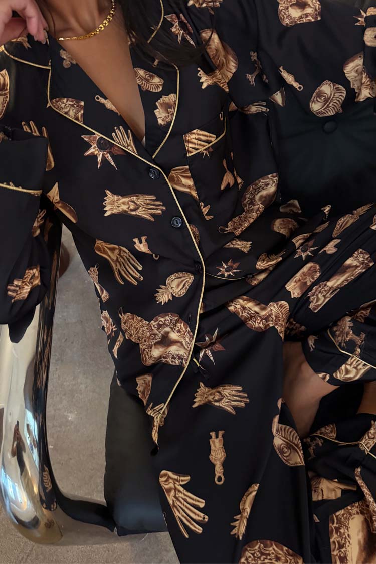 Deloris Button Through Pyjamas in black with gold hand, heart and eye motifs and contrast piping.