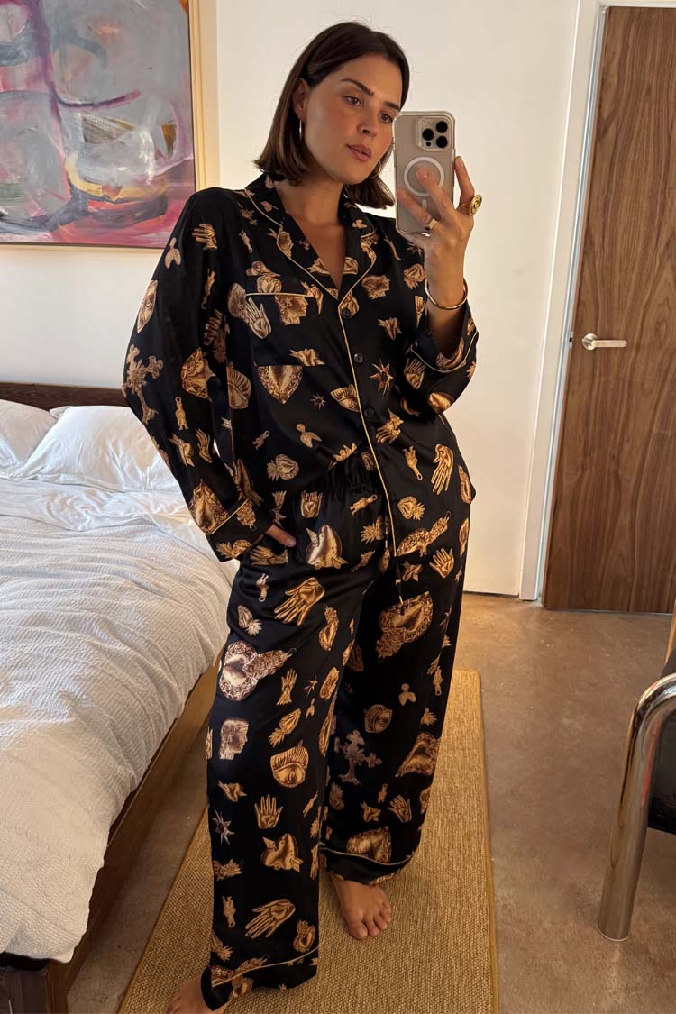 Black Deloris Button Through Pyjamas featuring gold hand, heart and eye prints, worn by a model in a mirror selfie.
