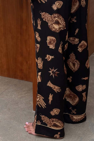 Deloris Button Through Pyjama bottoms in black, showcasing the gold hand, heart and eye print with piped hems.