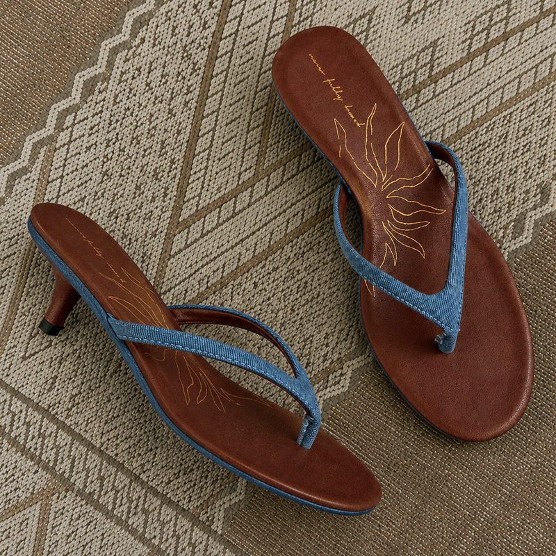 Denim Sandal Mules featuring slim blue straps, a low sculpted kitten heel, and brown cushioned soles with a sun motif.
