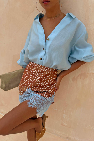 Fawn Mini Maeva Skirt with a brown animal print and blue lace hem, styled with a light blue shirt.