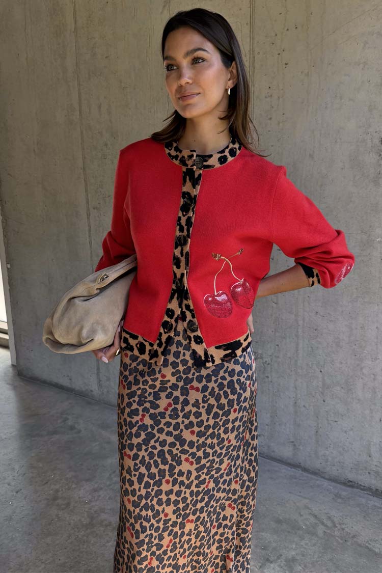 Red Cherry Holly Cardigan featuring leopard trim and cherry motifs, styled over a leopard print dress.