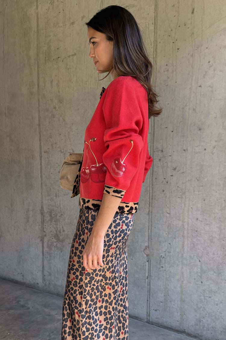 Red Cherry Holly Cardigan with embellished cherry motifs and leopard print trim, paired with a leopard skirt.