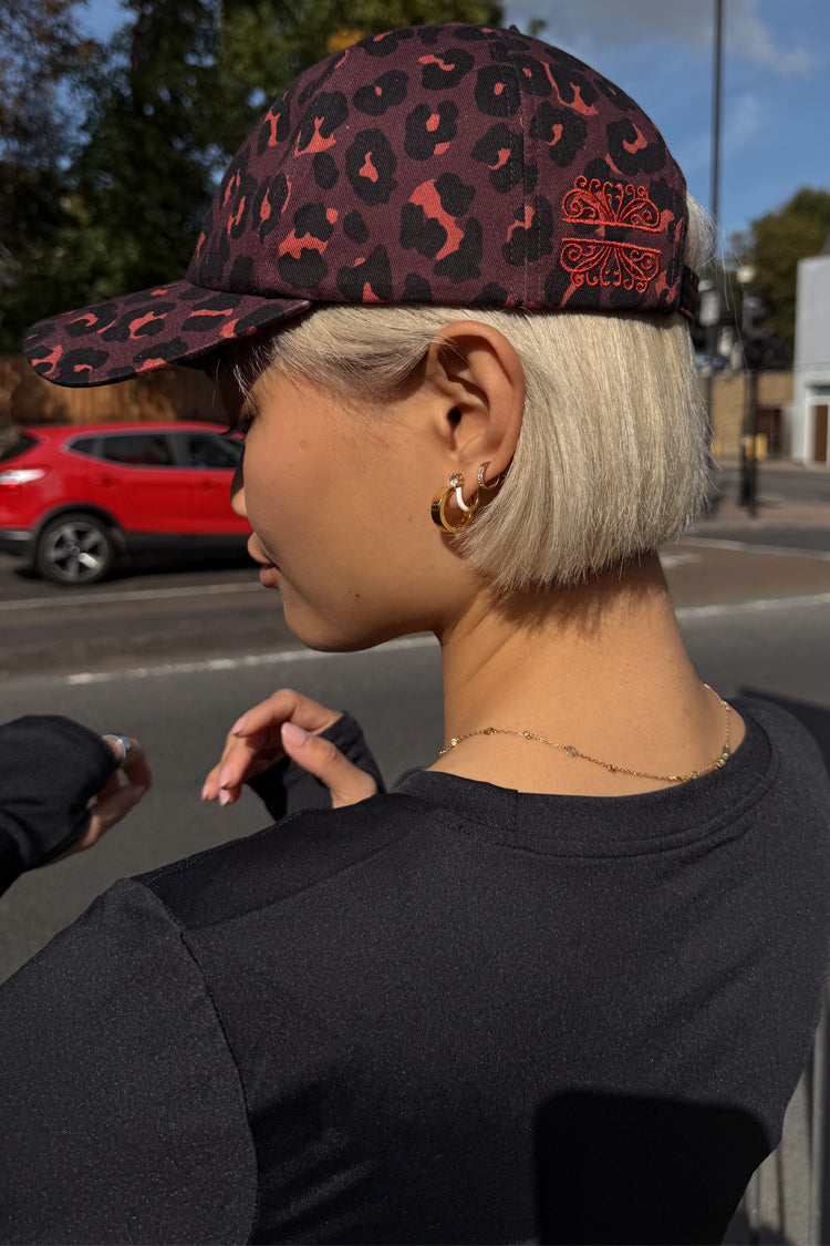 Dark Leopard Cap in iconic leopard print with burgundy tones and embroidered logo, styled on a model in a London street.