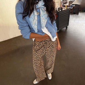Lucia Leopard Elissa Trousers featuring a wide-leg fit and iconic animal print, styled with a blue cardigan and scarf.
