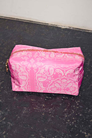 Vibrant pink bandana print make up bag with a white paisley pattern and gold-tone zip closure.