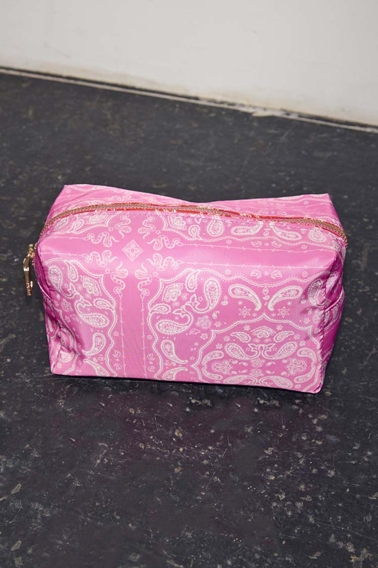 Vibrant pink bandana print make up bag with a white paisley pattern and gold-tone zip closure.