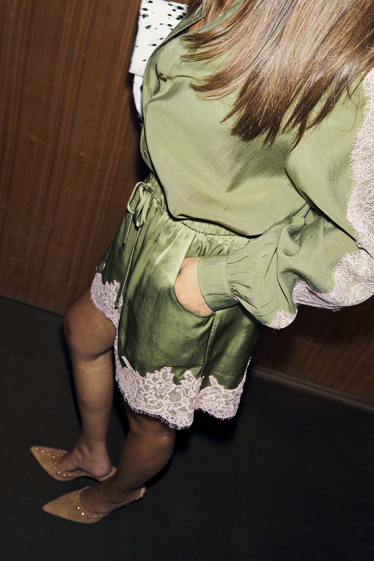 Shorts in pizzo verde oliva e rosa abbinati a una camicia coordinata e scarpe beige a punta.