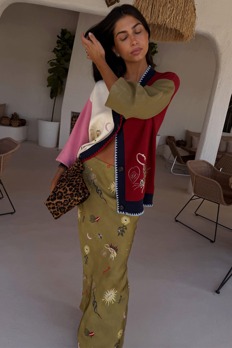 Cardigan Mystical Martha color block con ricami mistici, gonna verde oliva e pochette leopardata.