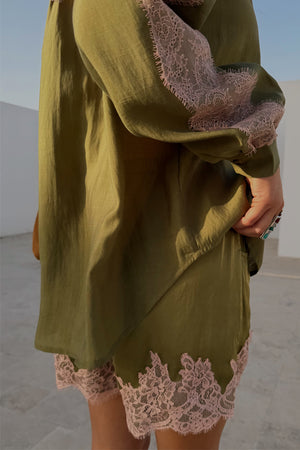 Pantaloncini verde oliva con pizzo rosa e camicia coordinata in un set estivo all'aperto.