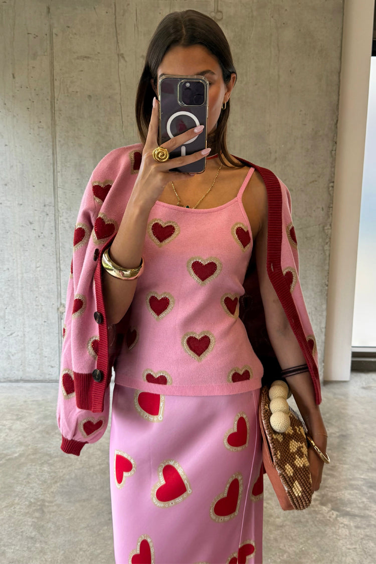 Top a canotta in maglia rosa con cuori rossi, abbinato a cardigan e gonna coordinati in un selfie.