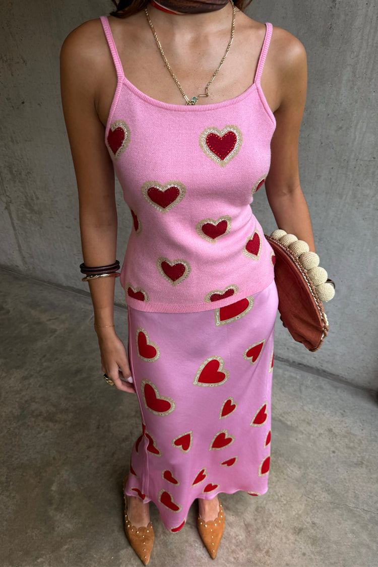 Canotta rosa in maglia con cuori rossi, abbinata a gonna midi coordinata e scarpe color cuoio.