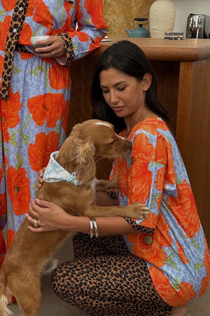 Blue Poppy Print Jersey Pyjamas with orange poppies and leopard trim, worn by a model cuddling a dog.