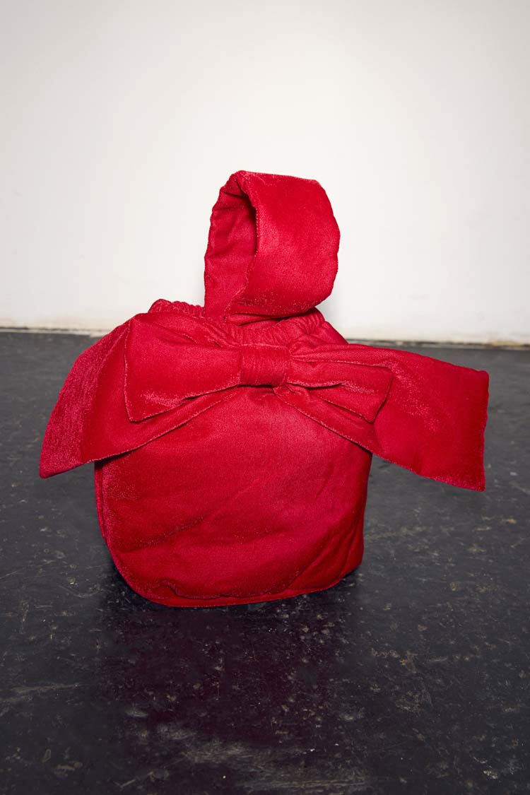 Red Velvet Bow Bag featuring a large bow and top handle, set against a neutral studio backdrop.