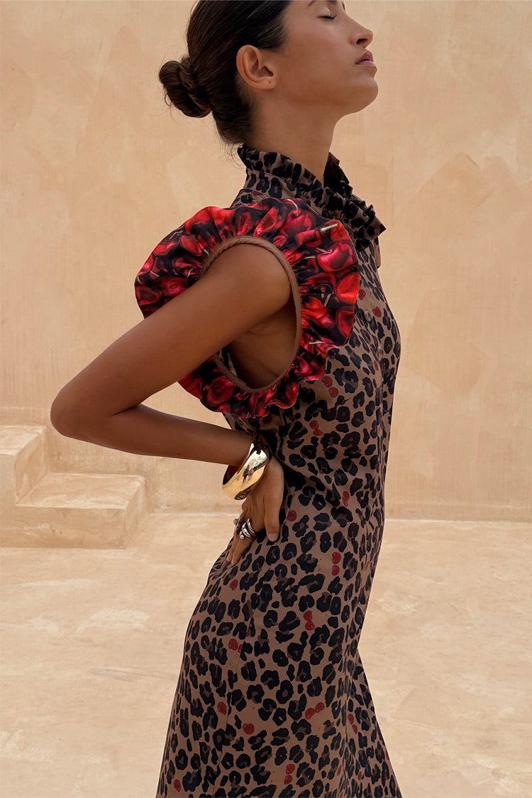 Abito Remi con stampa Cherry Leopard e maniche a sbuffo rosse, indossato di profilo su sfondo sabbia.