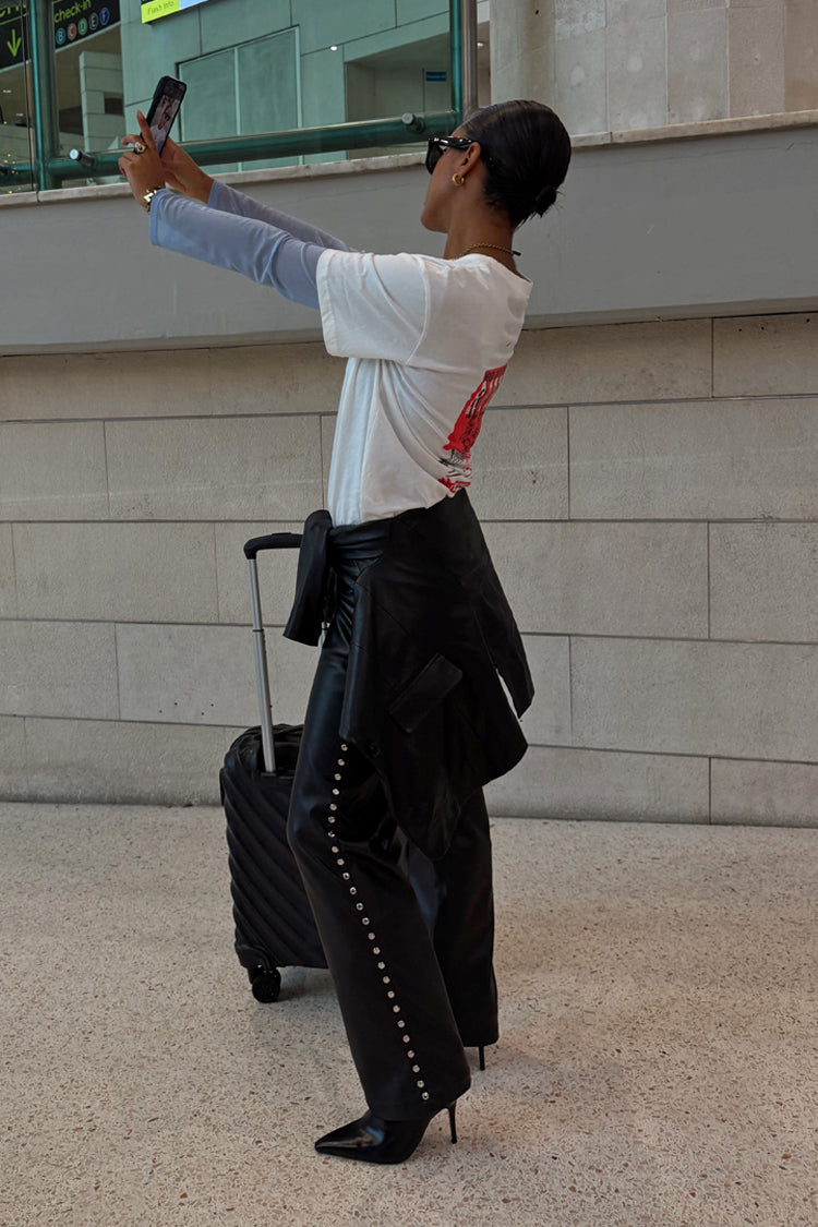 Black Vegan Leather Studded Leg Trousers with silver side studs, styled with a white tee and heels for a street style look.