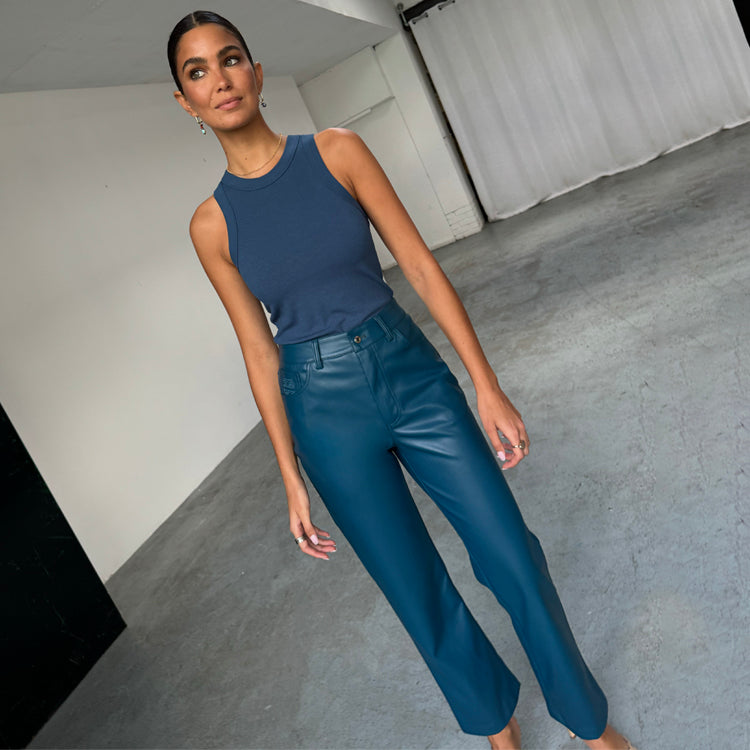 Pantaloni in pelle vegana ottanio a gamba dritta, abbinati a un top a canotta a coste blu.