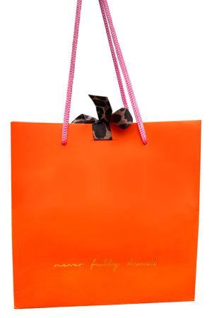 Vibrant orange NFD gift bag featuring gold foil branding, pink rope handles, and signature leopard print ties.